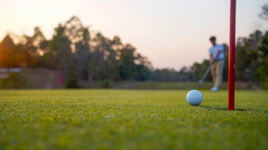 Golfçüler golfü akşam golf sahasına koyuyorlar. Golfçü golf topuna vuruyor. Spor tatil yaşam tarzı kavramı.