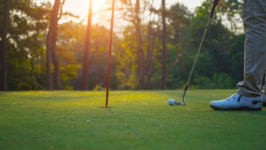 Golfçüler golfü akşam golf sahasına koyuyorlar. Golfçü golf topuna vuruyor. Spor tatil yaşam tarzı kavramı.