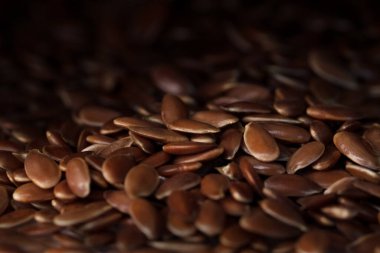 Işık demetinde keten tohumu veya keten tohumu koyu bulanık bir arkaplanda kaybolur.