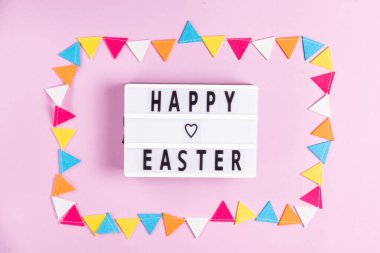 Pembe arka planda çok renkli keçeli kalemle çerçevelenmiş beyaz tahtadaki mutlu Paskalya yazıları