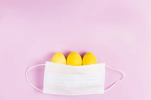 Drei Gelb Gefärbte Ostereier Mit Einer Schützenden Gesichtsmaske Auf Rosa — Stockfoto
