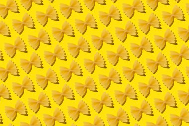 Sarı arka planda kusursuz çiğ İtalyan farfalle makarna deseni.