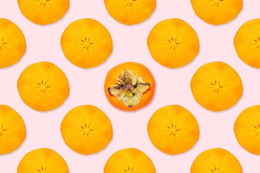 Turuncu hurma dilimleri pürüzsüz desenli ve pembe arkaplanda yaprakları olan bir hurma.