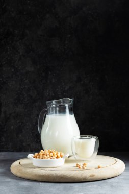 Alternatif vejetaryen sütü. Koyu bir arka planda, tahta bir tahtanın üzerinde cam bir sürahi içinde nohut.