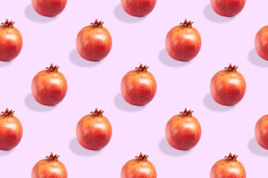 Pembe arka planda kusursuz olgun kırmızı nar deseni.