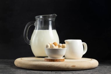 Orta Asya geleneksel kurut peyniri beyaz tabakta krema ve tahtadan bir sürahi sütle.