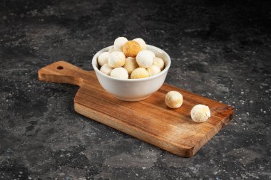 Central asian traditional cheese kurut in a white plate on a wooden board on a dark background clipart
