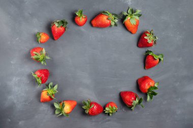 Tebeşir tahtası fotokopi alanının arka planında yeşil yapraklı olgun kırmızı çileklerden çerçeve