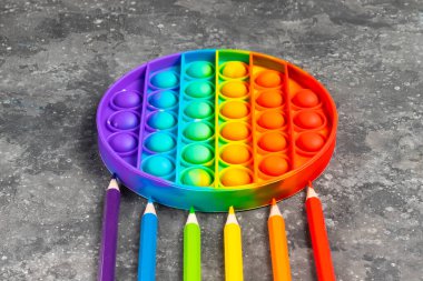 Çocukların silikon oyuncağı anti-stresi patlat ya da koyu bir arka planda gökkuşağının her renginde kalemlerle basit bir gamzesi olsun.