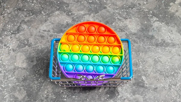 Rainbow silicone antistress pop it or simple simple in mini grocery basket on gray background