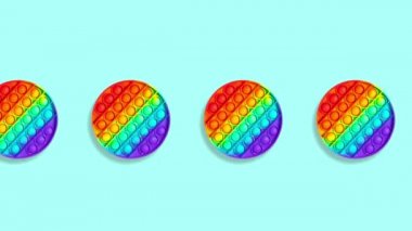 Kusursuz Durma Hareketi Animasyonu. Yuvarlak gökkuşağı silikon çocuklar oyuncaklar antistresi patlat ya da mavi arka planda bir çizgi boyunca basit bir gamze taşı