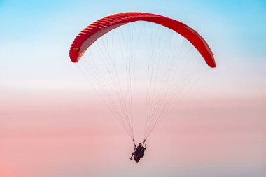 Gökyüzünde paraşütle atlıyor. Paraglider gün batımında dağlarla birlikte denizin üzerinde uçuyor. Oludeniz, Mugla, Türkiye 'de paraglider ve Mavi Göl' ün hava manzarası.
