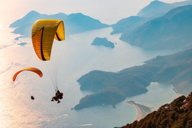 Gün batımında Oludeniz üzerinde uçan paraglider ikilisi. Fethiye, Mugla.