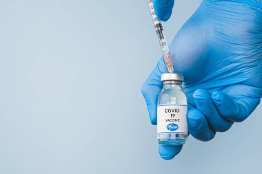 İzmir, Türkiye - 17 Ocak 2021: Coronavirus aşısı kavramı ve geçmişi. Yeni aşı pfizer ve biyoteknoloji mavi arka planda izole edildi. Covid-19, 2019-nCov salgını.