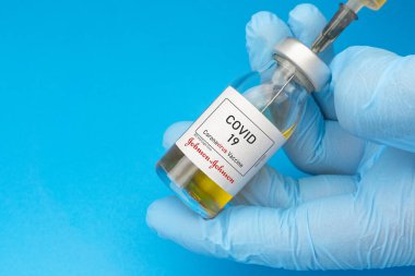 İzmir, Türkiye - 11 Ağustos 2021: Coronavirus aşısı kavramı ve geçmişi. Yeni aşı Johnson ve Johnson (veya JNJ-78436735) mavi arka planda izole edilmiştir. Covid-19, 2019-nCov salgını.