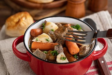 Kırmızı kasede havuç ve patates ve çatallı sığır eti yahnisi.