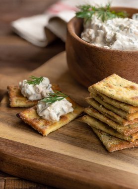 Kremalı jalapeno sosu, tahtadan yapılmış taze dereotuyla süslenmiş krakerler.