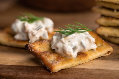 Ahşap bir masada taze dereotuyla süslenmiş kremalı jalapeno sosu ve kraker.