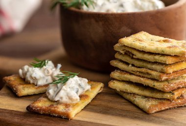 Kremalı jalapeno sosu, tahtadan yapılmış taze dereotuyla süslenmiş krakerler.