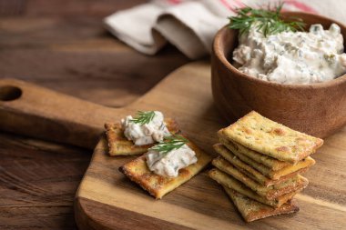 Kremalı jalapeno sosu, tahtadan yapılmış taze dereotuyla süslenmiş krakerler.