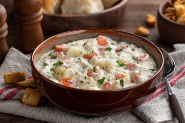 Bir kase kremalı patates ve kırsal ahşap masada kızarmış ekmek ve havuç çorbası.