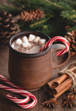 Bir fincan sıcak çikolata, bastonlu şeker ve kırsal bir ahşap masa üzerinde lokum.