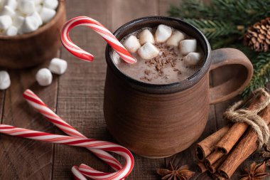 Bir fincan sıcak çikolata, bastonlu şeker ve kırsal bir ahşap masa üzerinde lokum.