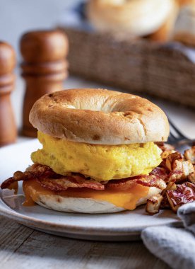 Kahvaltıda yumurta, pastırma ve peynirli sandviç ve kızarmış patates.