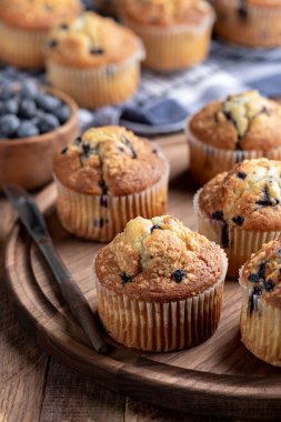 Böğürtlenli kekler ahşap bir tabakta ve arka planda meyveli kekler.