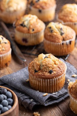 Kumaş peçetede yaban mersinli kek ve arka plandaki soğutma rafında kekler.