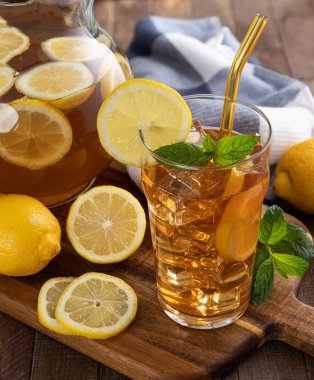 Bir bardak buzlu çay ve ahşap bir masada limon dilimleri.