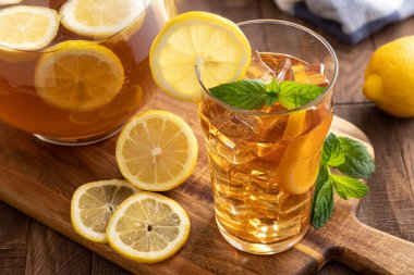 Bir bardak buzlu çay ve ahşap bir masada limon dilimleri.