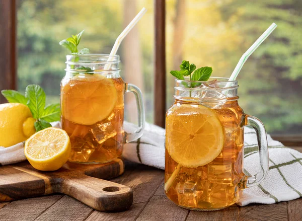 国の風景を背景に レモンとミントの氷茶の2つの飲料ガラス瓶 — ストック写真