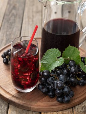 Taze üzümlü bir bardak üzüm suyu ve ahşap bir masada sürahi. 