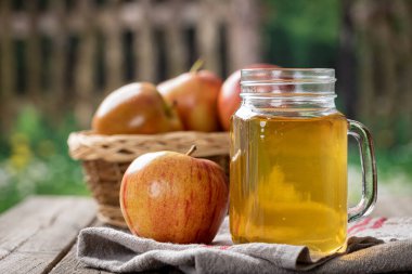 Kırsal bir zeminde, bir bardak elma suyu ve taze elmalar.