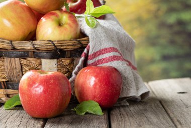 Kırsal ahşap bir masada kırmızı elmaların açık havada yakın plan çekimi ve fotokopi alanı olan bir sepetin içinde.