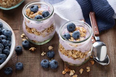 Yaban mersinli yoğurt ve ahşap masada taze yaban mersinli granola parfe.