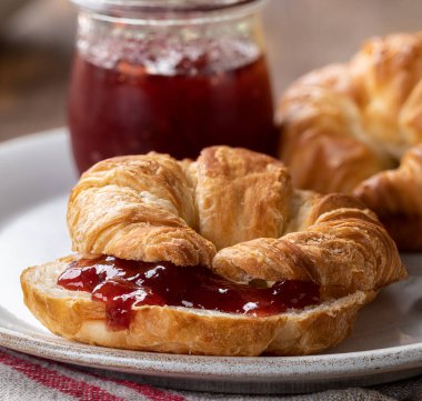 Bir tabakta çilek reçeli ile kaplanmış kruvasan.