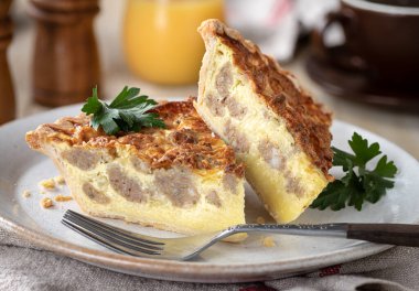 Arka planda kahve ve meyve suyu olan bir tabakta iki dilim sosisli börek.