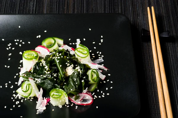 Vegetarian wakame salad on black plate — Stock Photo, Image