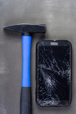 Smartphone with broken glass and hammer