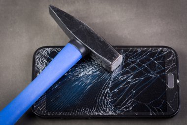 Smartphone with broken glass and hammer