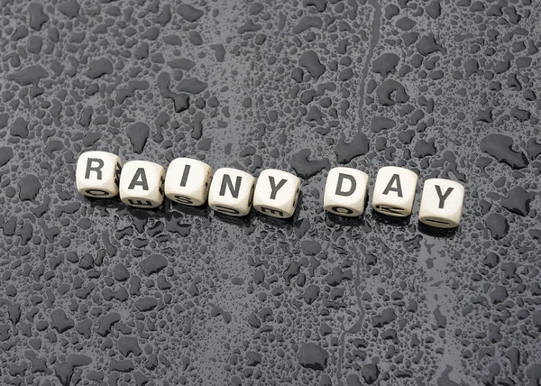 'Rainy Day' deletreado en un capó de coche empapado de lluvia . Fotos De Stock Sin Royalties Gratis