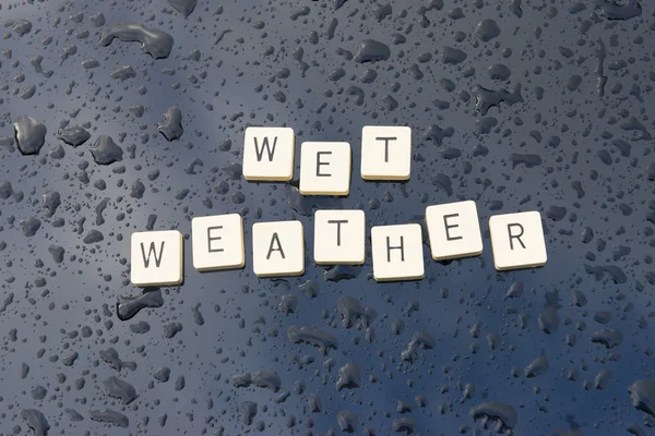 'Wet Weather' se deletrea en un capó empapado de lluvia . Fotos De Stock Sin Royalties Gratis