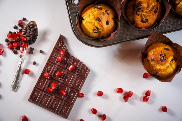 Chocolate muffins with a chocolate bar and red pomegranate fruit — Stock Photo, Image