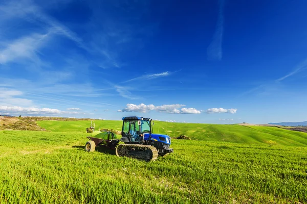 Tractor on tracks in the summer sunny day on a green field. — Stock Photo, Image