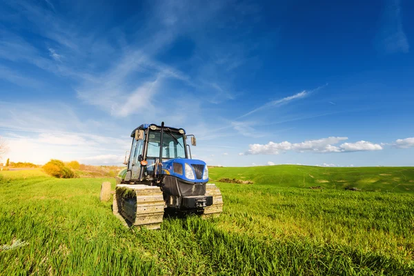 Traktor auf Schienen an einem sonnigen Sommertag auf der grünen Wiese. — Stockfoto