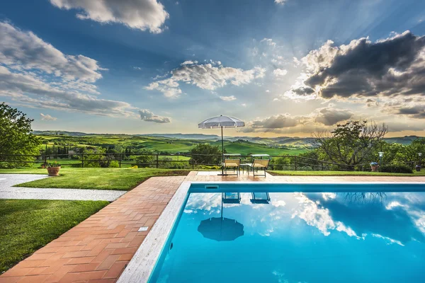 Espreguiçadeiras à beira da piscina em um dia quente ao pôr do sol . — Fotografia de Stock