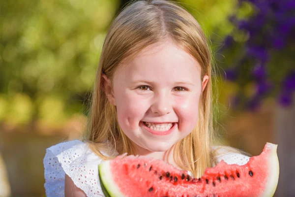 Šťastná dívka s velkým červeným dílek melounu sedí na rustikální ta — Stock fotografie