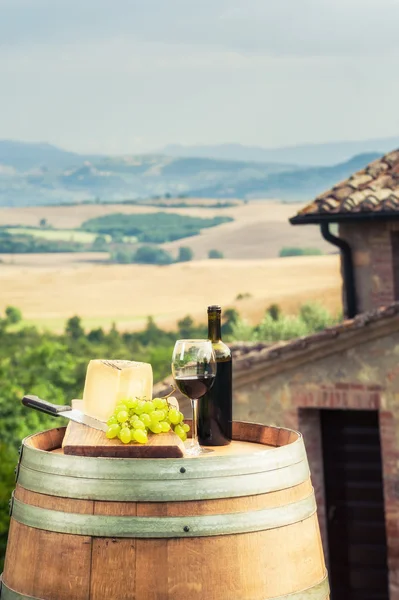 Vino tinto, queso y uvas sobre un fondo del landsc toscano —  Fotos de Stock